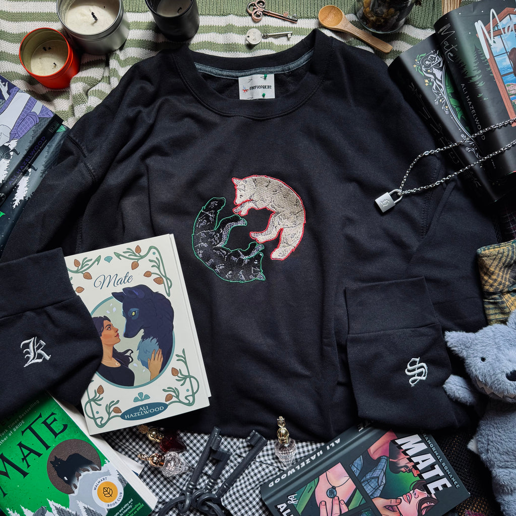 Black sweatshirt with wolf design on a surface with books and other items