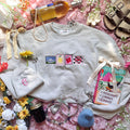 Beige sweatshirt with stamps embroidered on the front.