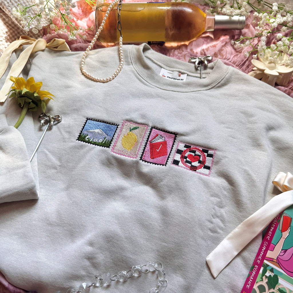 Beige sweatshirt with stamps embroidered on the front.