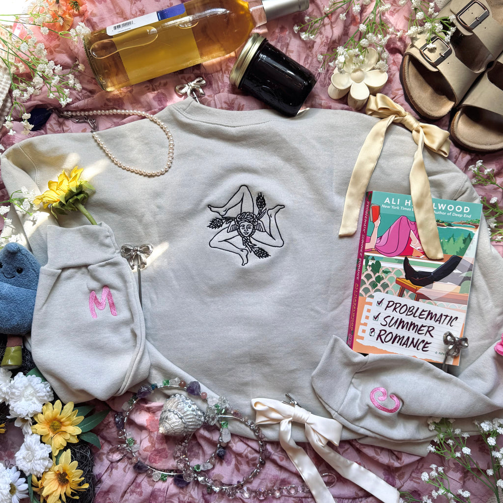 Beige sweatshirt with embroidered design on the back.