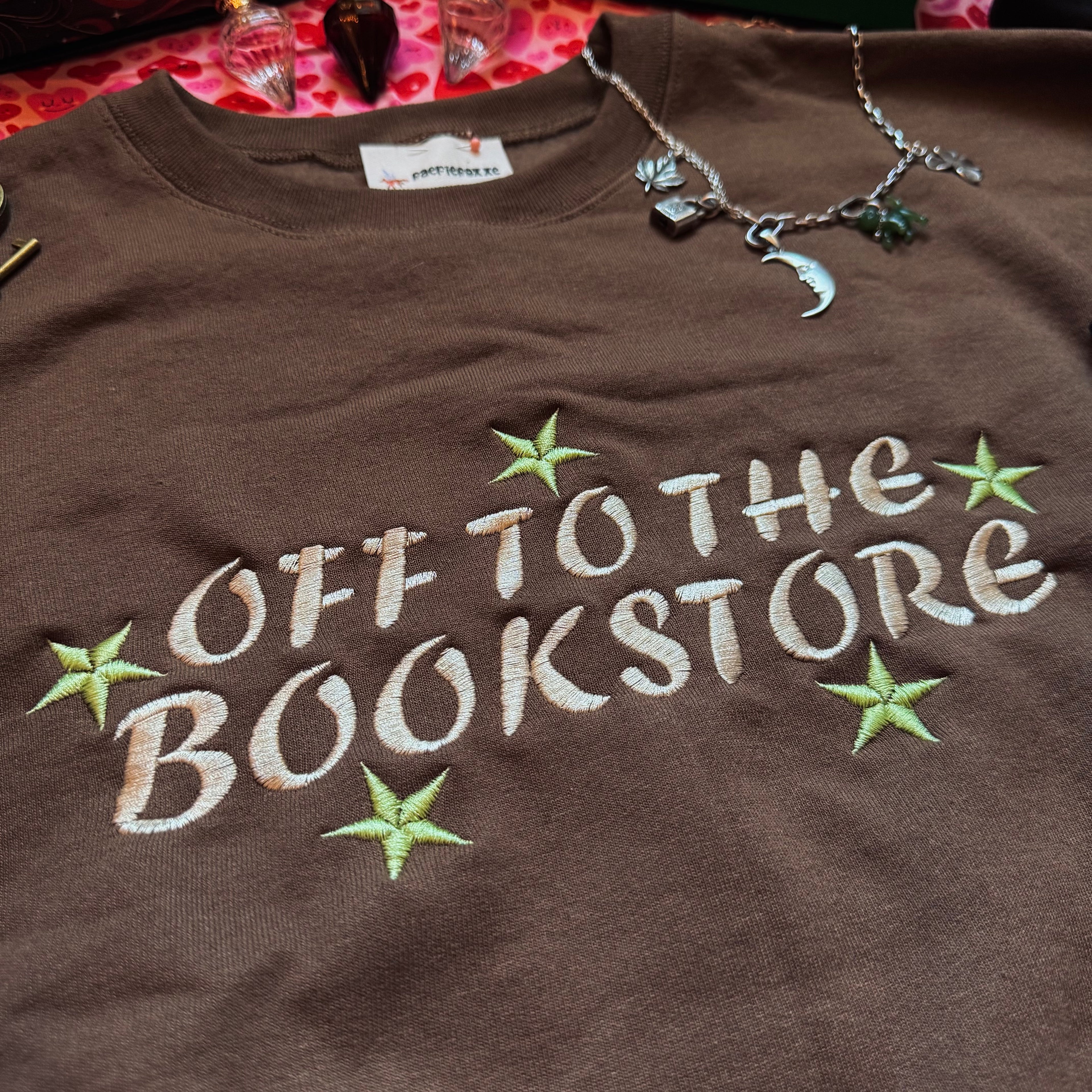 Brown sweatshirt with 'Off to the Bookstore' text and stars.