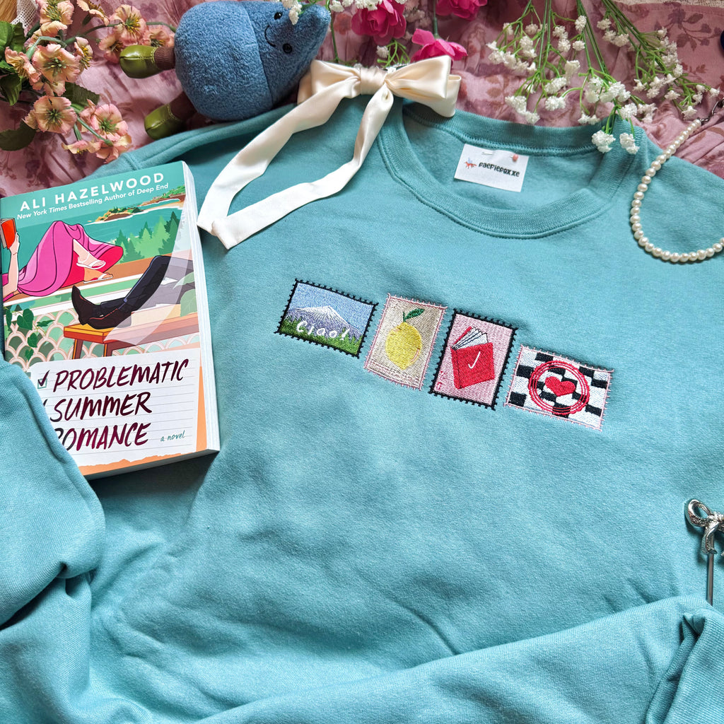 Teal sweatshirt with embroidered stamp designs.