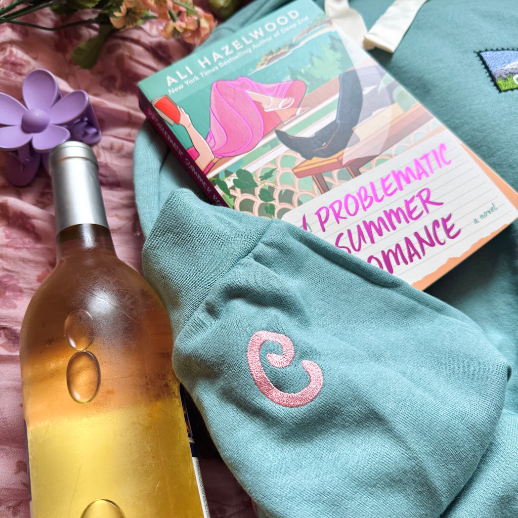Teal sweatshirt with embroidered "C" design on sleeve.