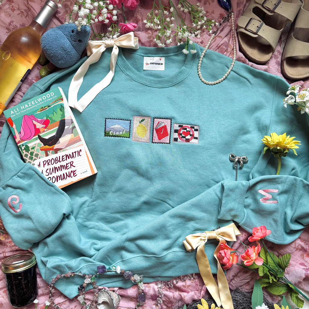 Teal sweatshirt with embroidered stamp designs.