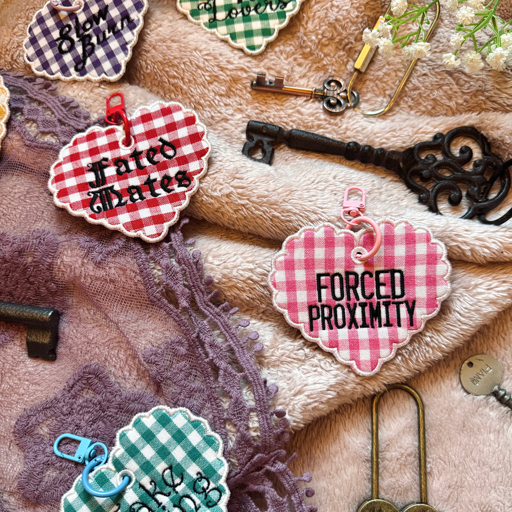 Decorative keychains with text on a textured surface with keys and lace.