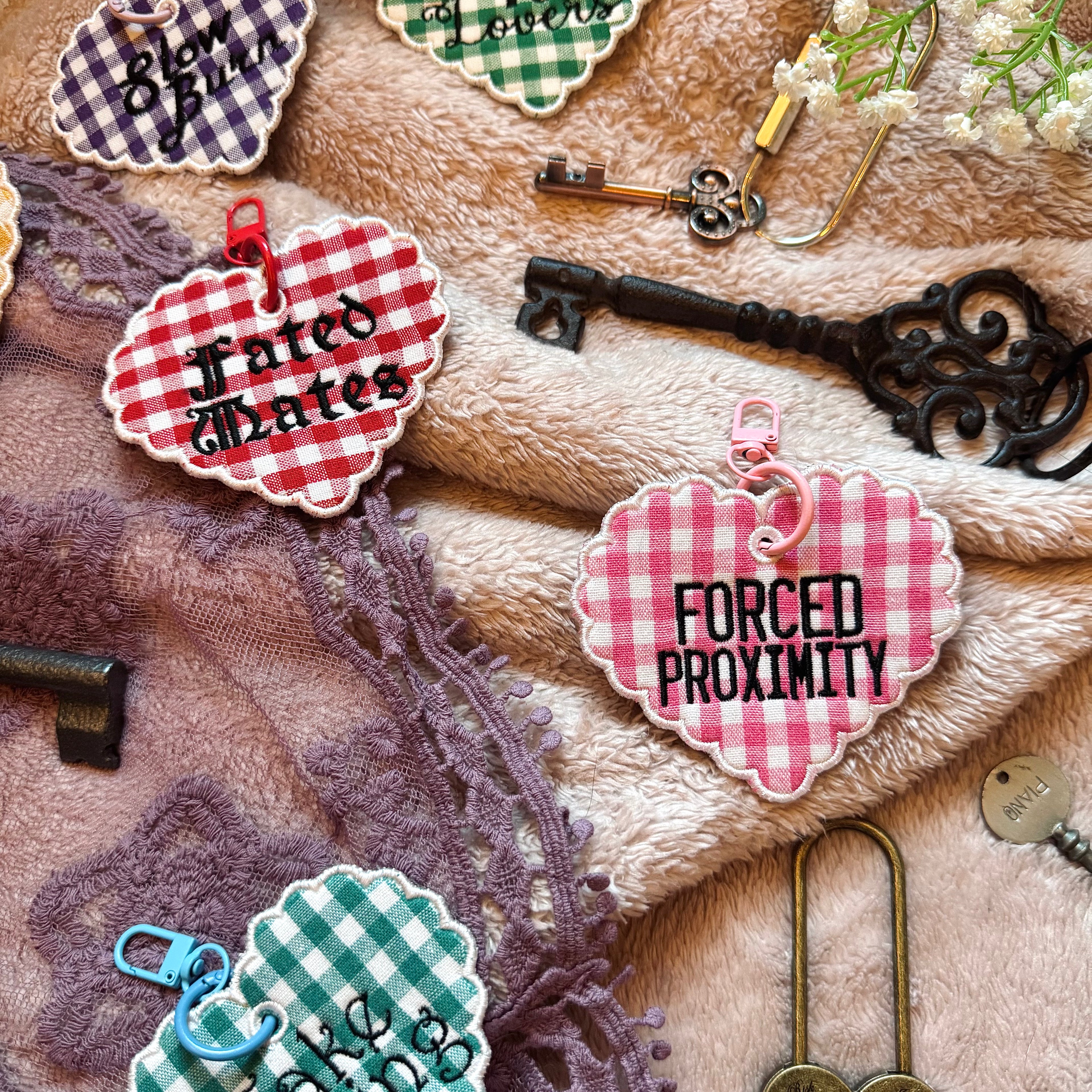 Decorative keychains with text on a textured surface with keys and lace.