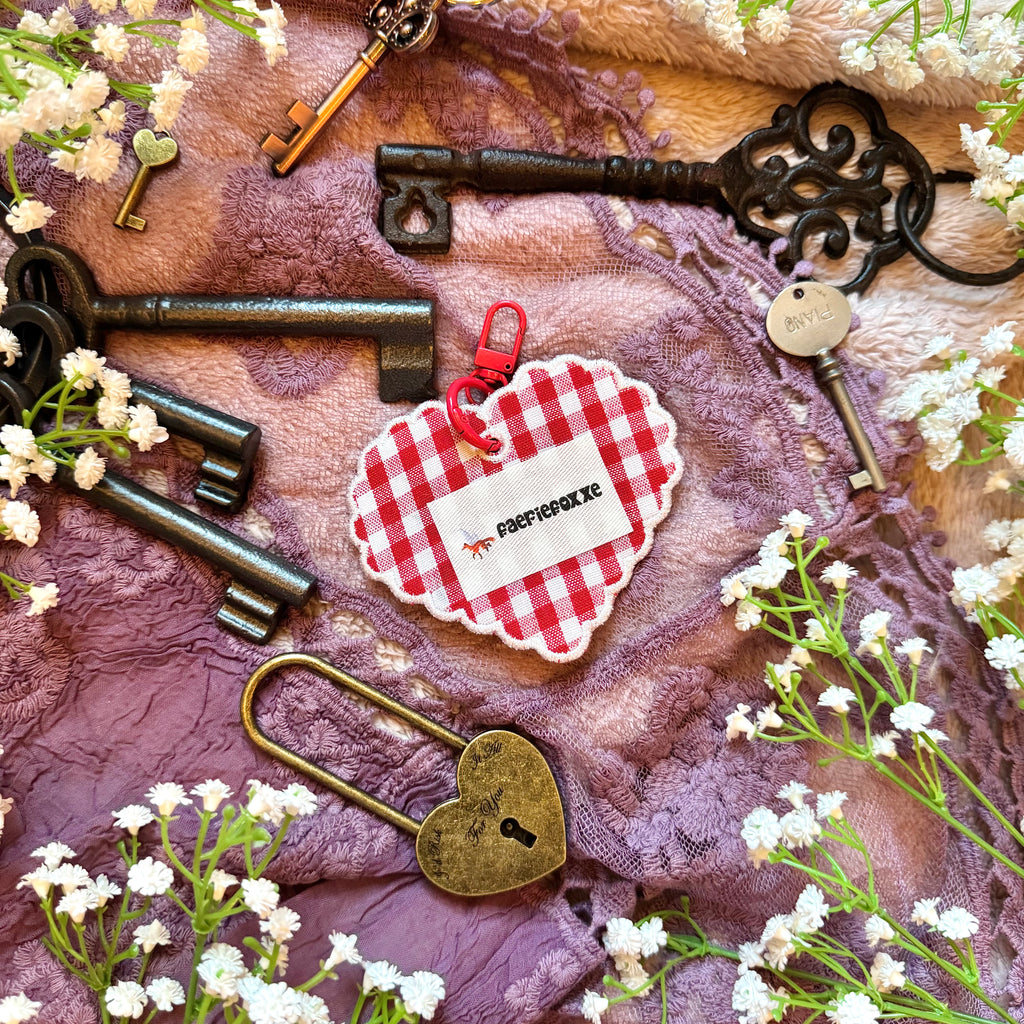 Decorative keys and a heart-shaped lock on a textured fabric background with small white flowers.
