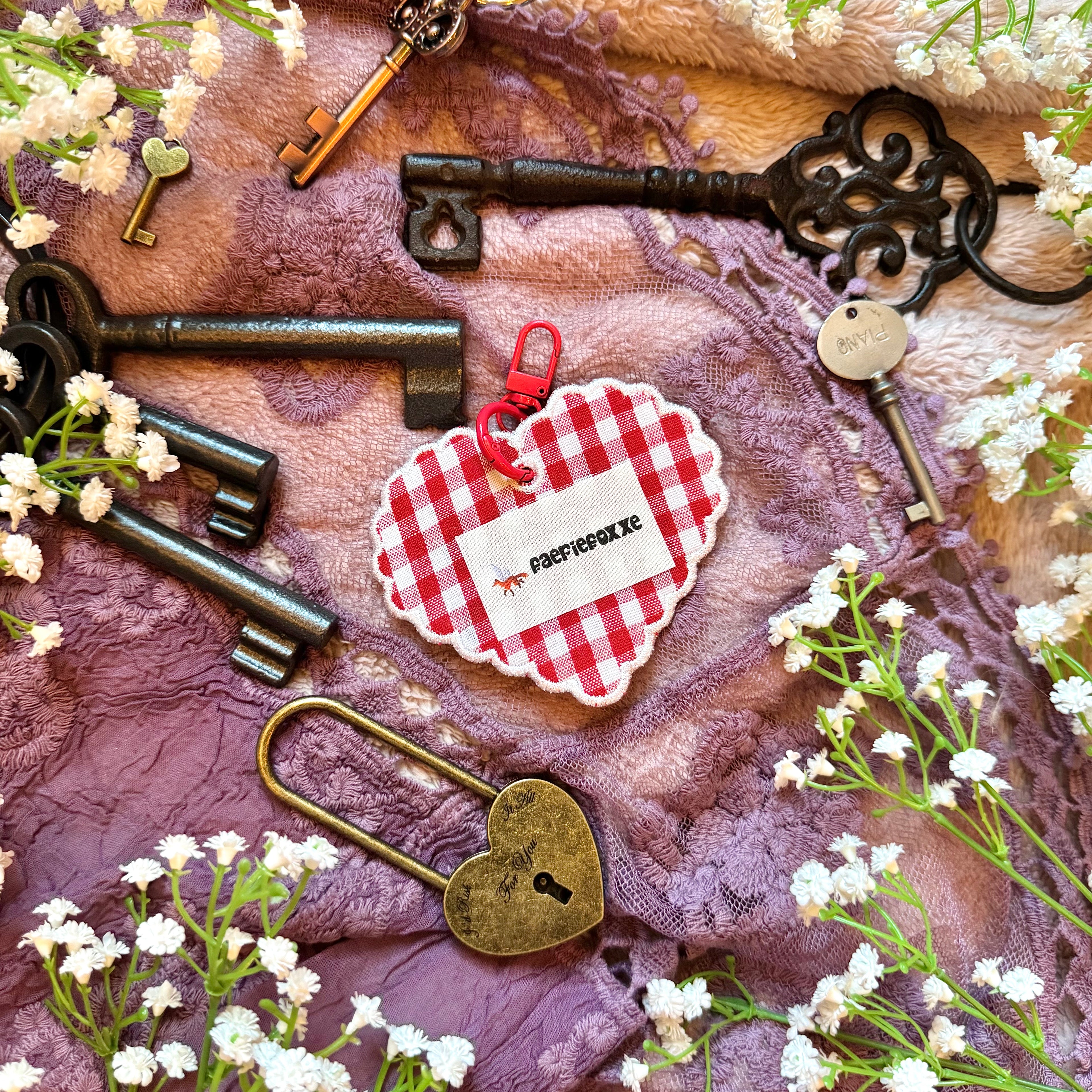 Decorative keys and a heart-shaped lock on a textured fabric background with small white flowers.