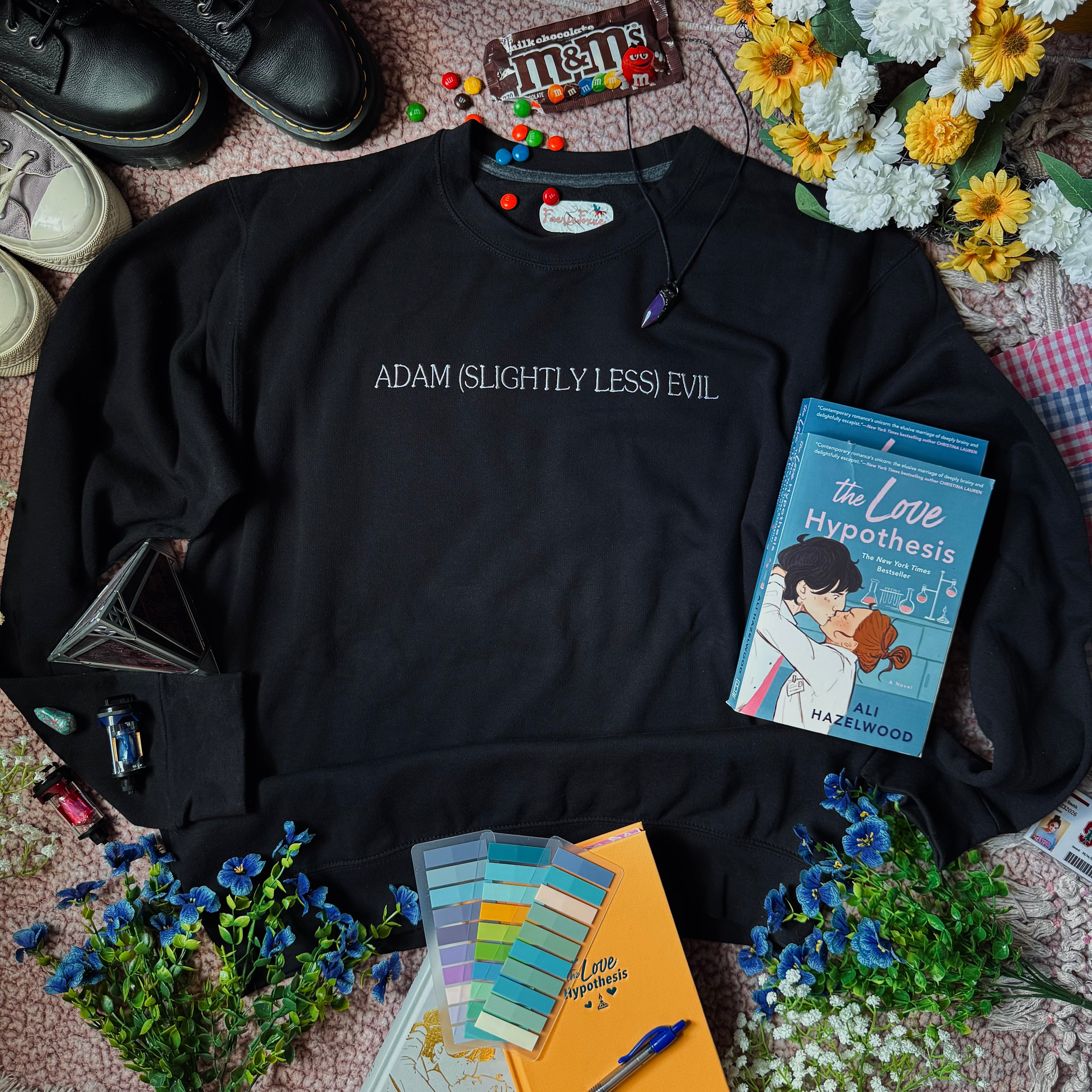 A black crewneck sweatshirt with the text 'ADAM (SLIGHTLY LESS) EVIL' printed in white across the chest.