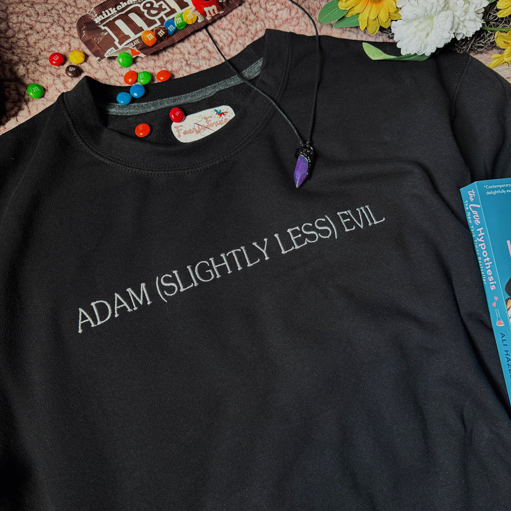 A black crewneck sweatshirt with the text 'ADAM (SLIGHTLY LESS) EVIL' printed in white across the chest.