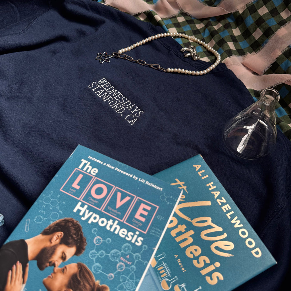 Navy crewneck with embroidered words "Wednesdays. Stanford, CA." on the back under the neckband.