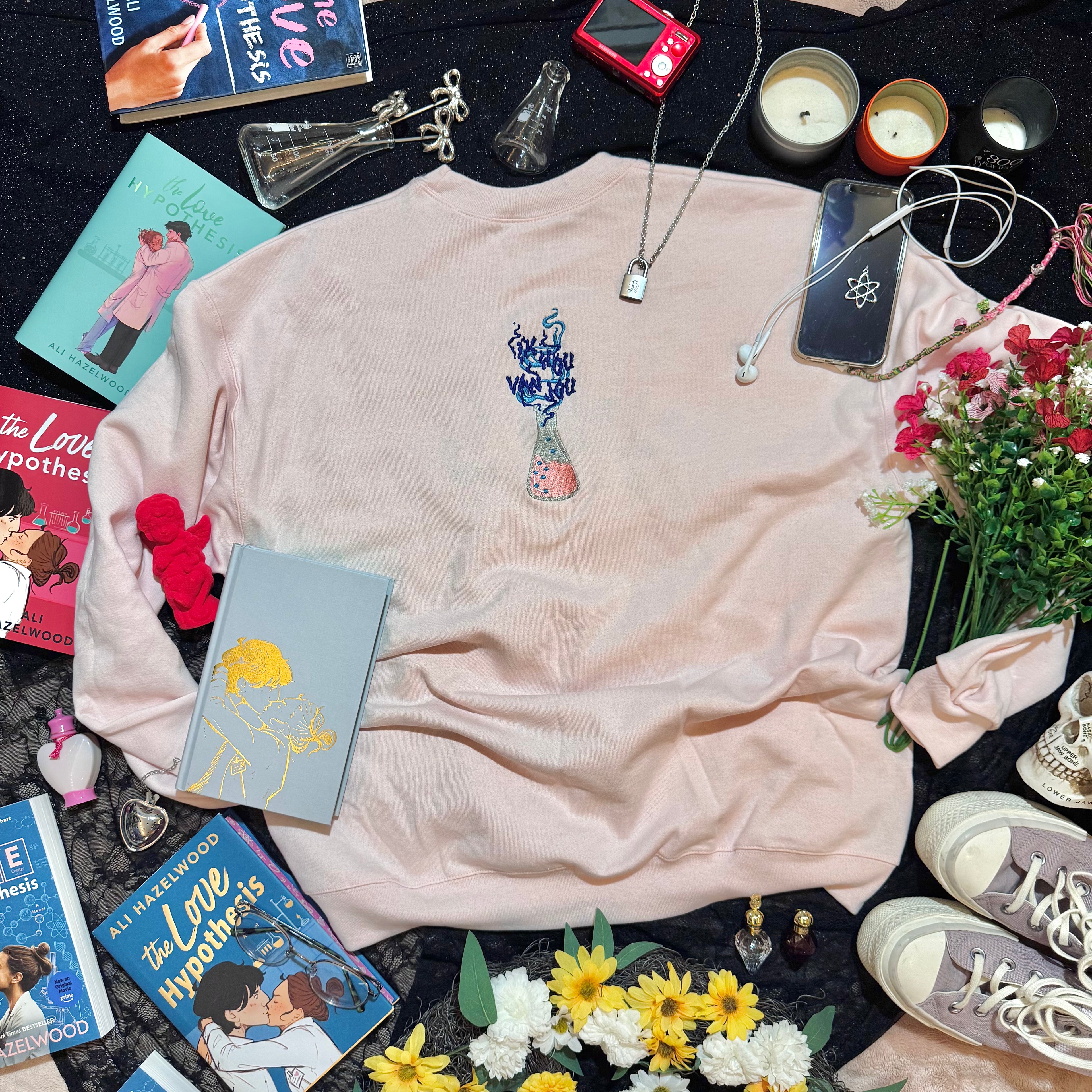 Baby pink sweatshirt with an embroidered erlenmeyer flask that has smoke that spells out "Ik Hou Van Jou."